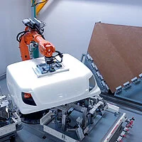Ein Roboterarm transportiert ein großformatiges Bauteil